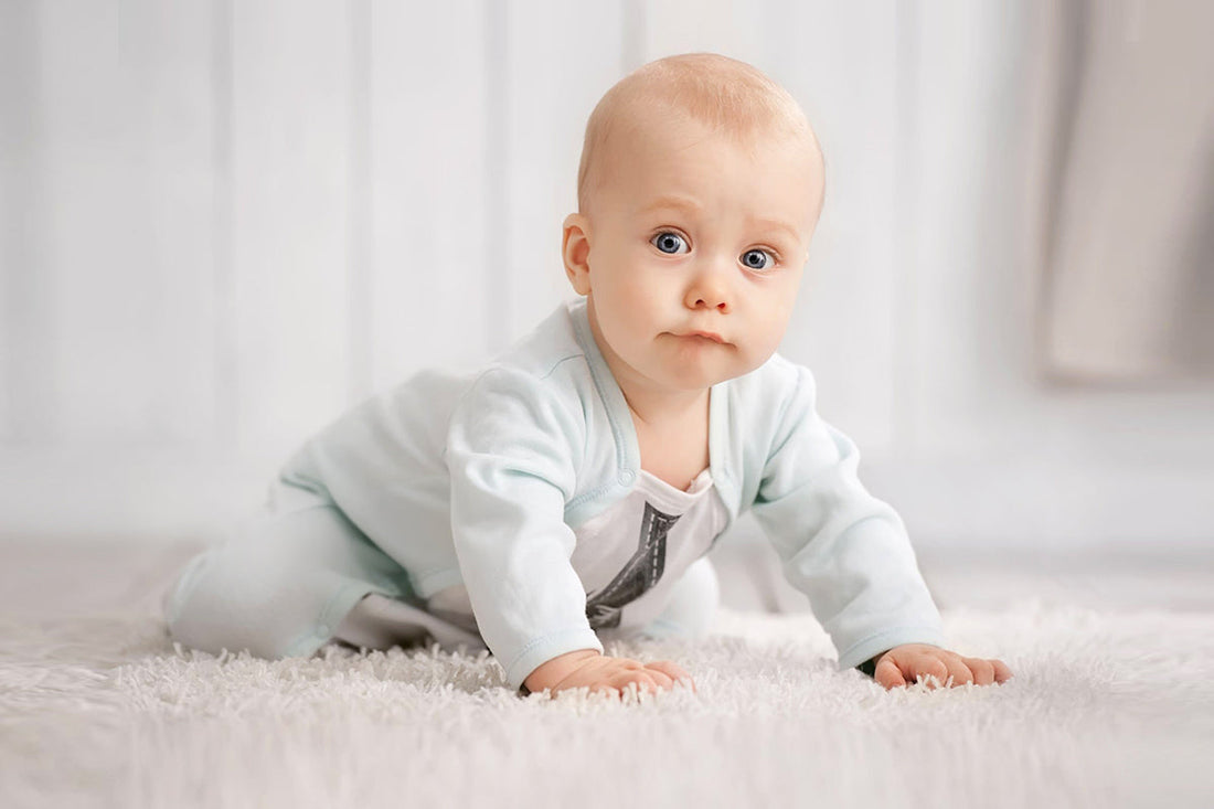 A baby is doing tummy time on a soft carpet, lifting their head and looking forward, showing early crawling and motor development.