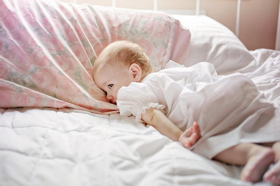 A baby peacefully lying on a bed, wrapped in a soft blanket.